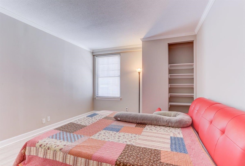 Bedroom with crown molding, a textured ceiling, and wood finished floors