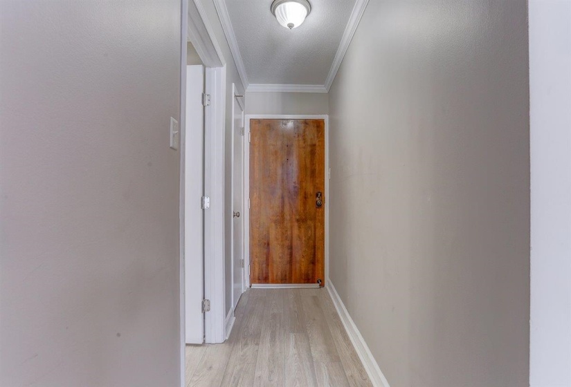 Hallway featuring crown molding and light wood-type flooring