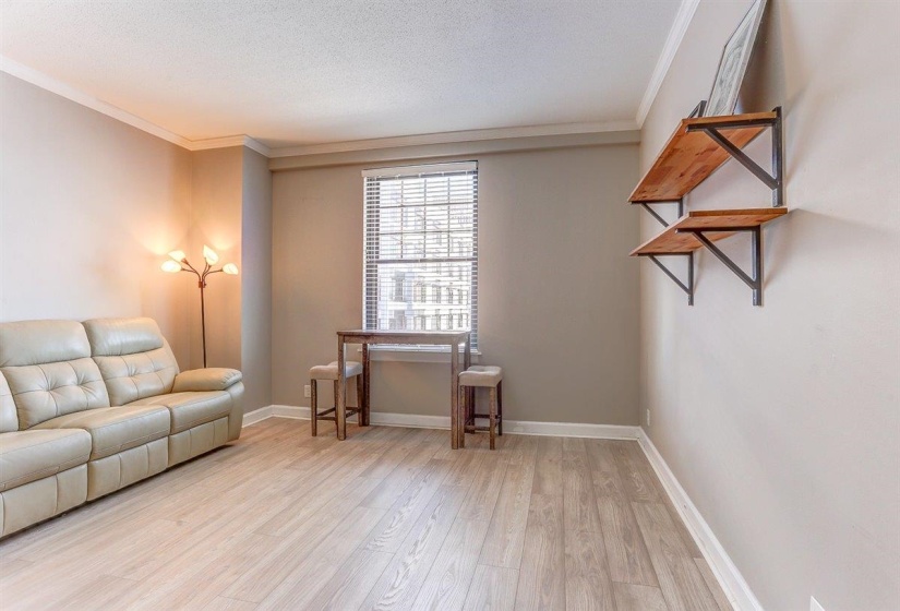 Living area with crown molding, light wood-style flooring, and a textured ceiling