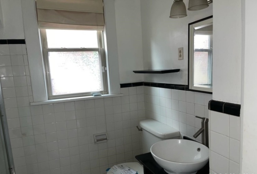 Full bath with tile walls, vanity, and a wainscoted wall