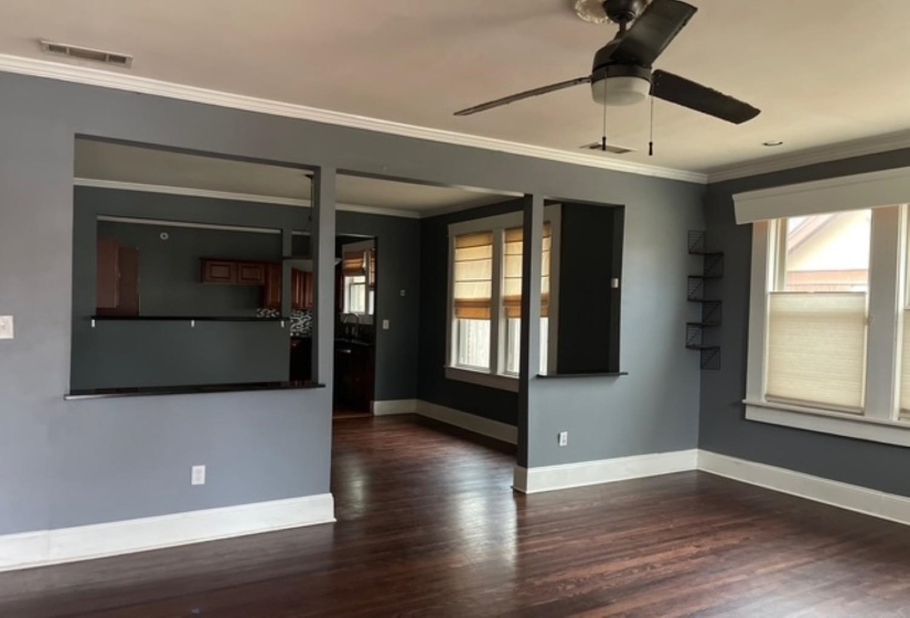 Spare room with crown molding, dark wood-style floors, healthy amount of natural light, and a ceiling fan