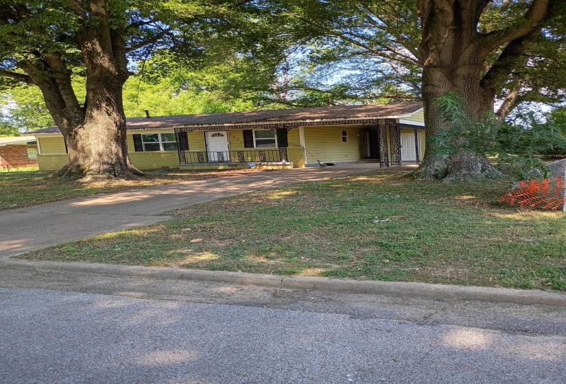 Ranch-style home with concrete driveway, covered porch, and a carport