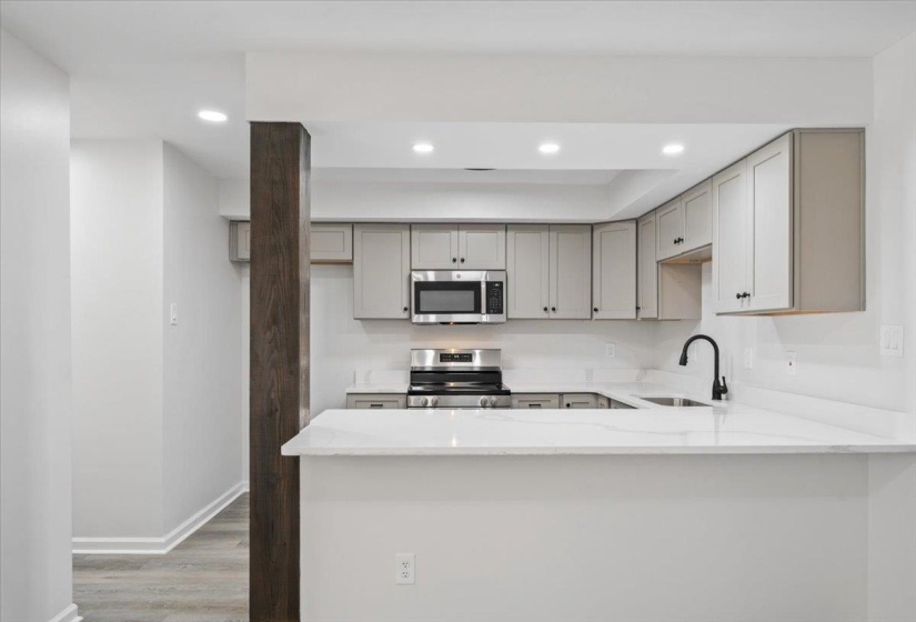 Kitchen featuring appliances with stainless steel finishes, gray cabinetry, light stone countertops, light wood-type flooring, and recessed lighting