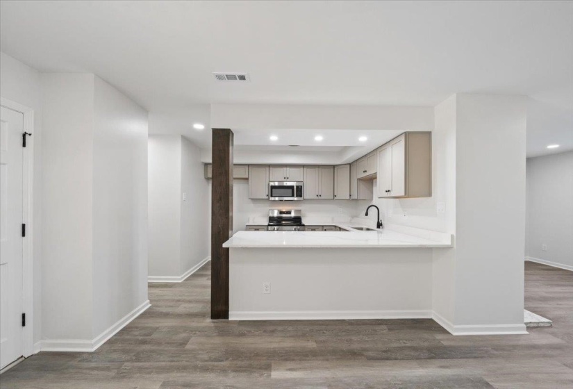 Kitchen with gray cabinets, light wood finished floors, appliances with stainless steel finishes, recessed lighting, and a peninsula