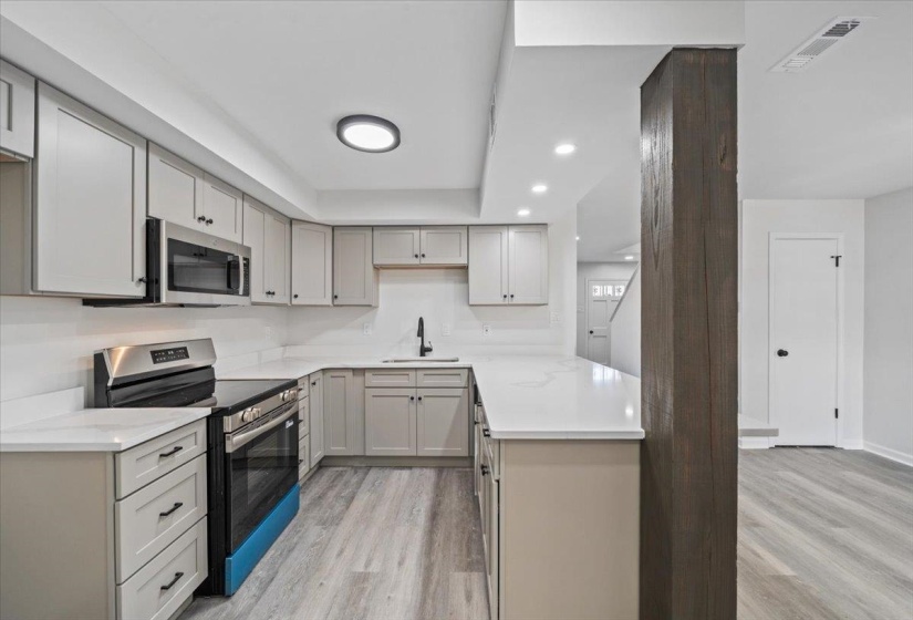 Kitchen with appliances with stainless steel finishes, light wood-type flooring, recessed lighting, and light stone countertops