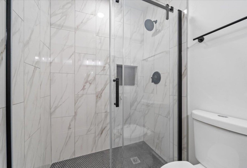 Full bath featuring toilet and a marble finish shower