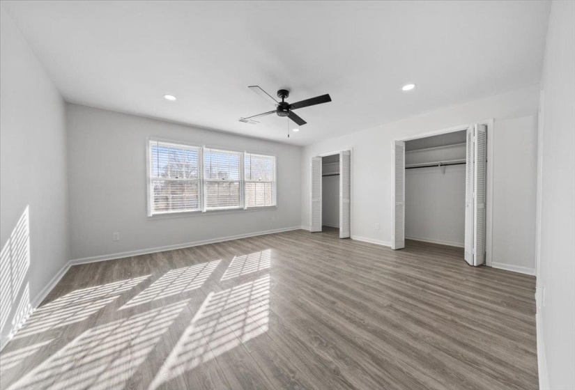 Unfurnished bedroom with two closets, a ceiling fan, wood finished floors, and recessed lighting