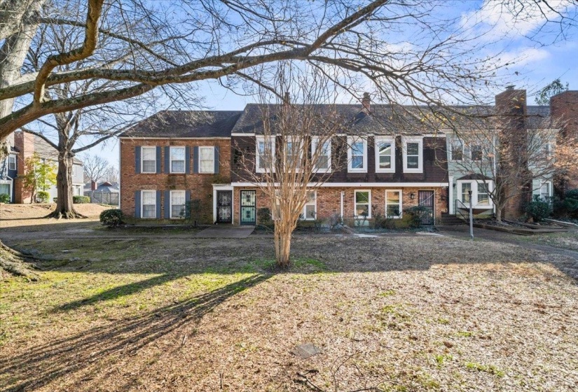 View of front of home featuring brick siding, a front lawn, and a chimney