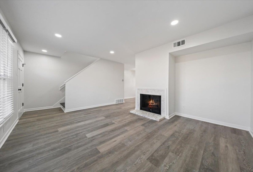 Unfurnished living room with a fireplace, wood finished floors, recessed lighting, and stairs