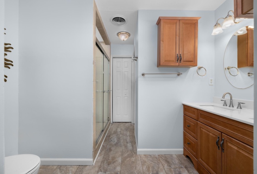 Full bathroom with vanity, a shower stall, and a closet