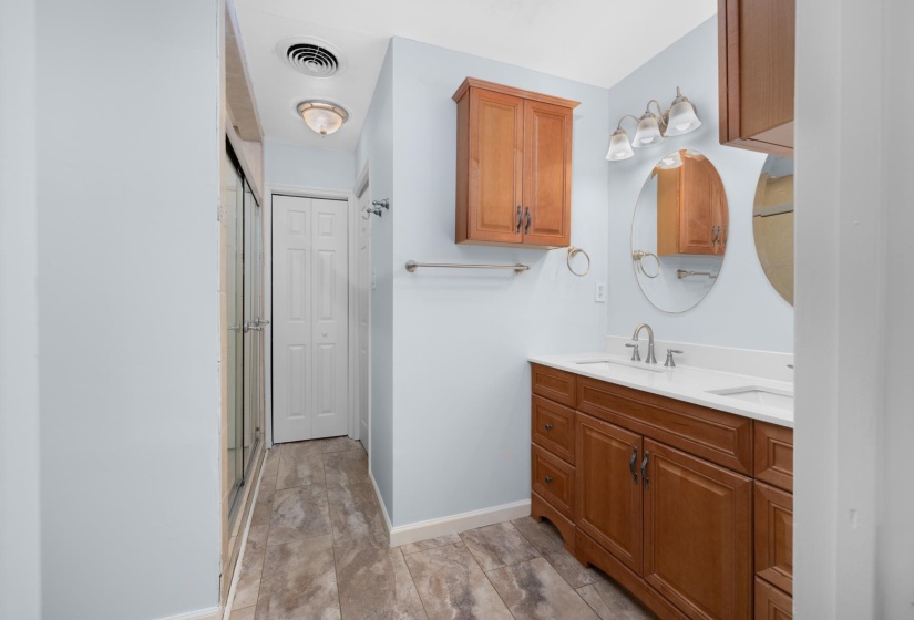 Bathroom featuring double vanity, a shower with door, and a closet