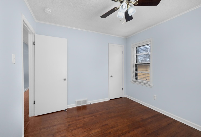 Unfurnished bedroom featuring dark wood-type flooring, crown molding, ceiling fan, and a textured ceiling