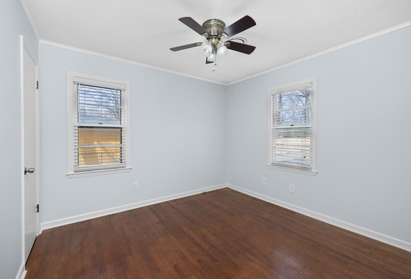 Unfurnished room featuring dark wood finished floors, ornamental molding, and a ceiling fan