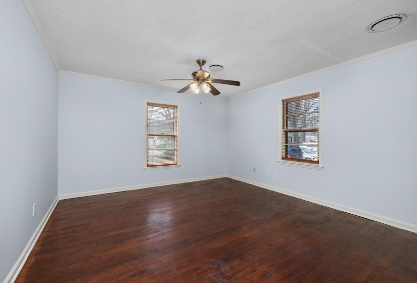 Spare room with dark wood-type flooring, a textured ceiling, ornamental molding, and a ceiling fan
