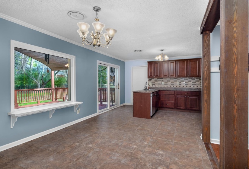 Kitchen featuring a chandelier, healthy amount of natural light, ornamental molding, tasteful backsplash, and pendant lighting
