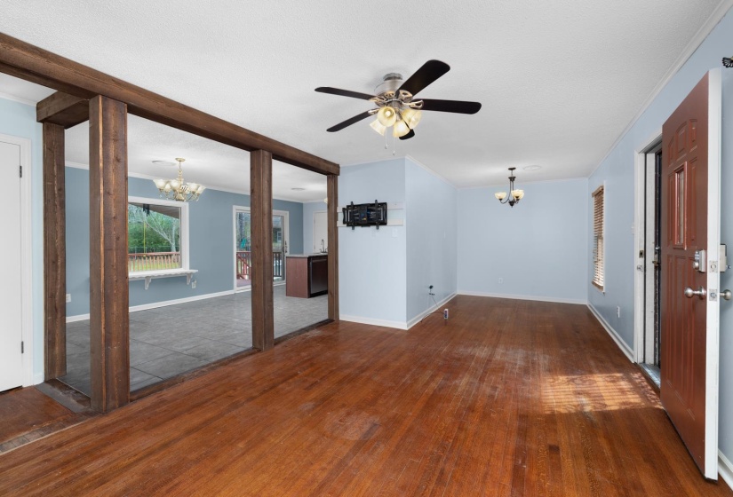 Unfurnished living room with a chandelier, crown molding, dark wood finished floors, and ceiling fan