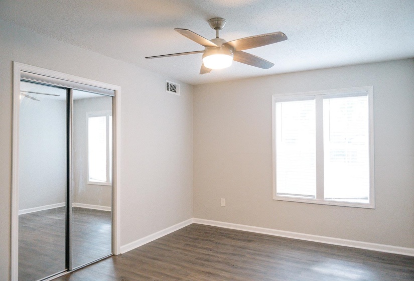 Unfurnished bedroom with a textured ceiling, ceiling fan, a closet, and dark hardwood / wood-style flooring
