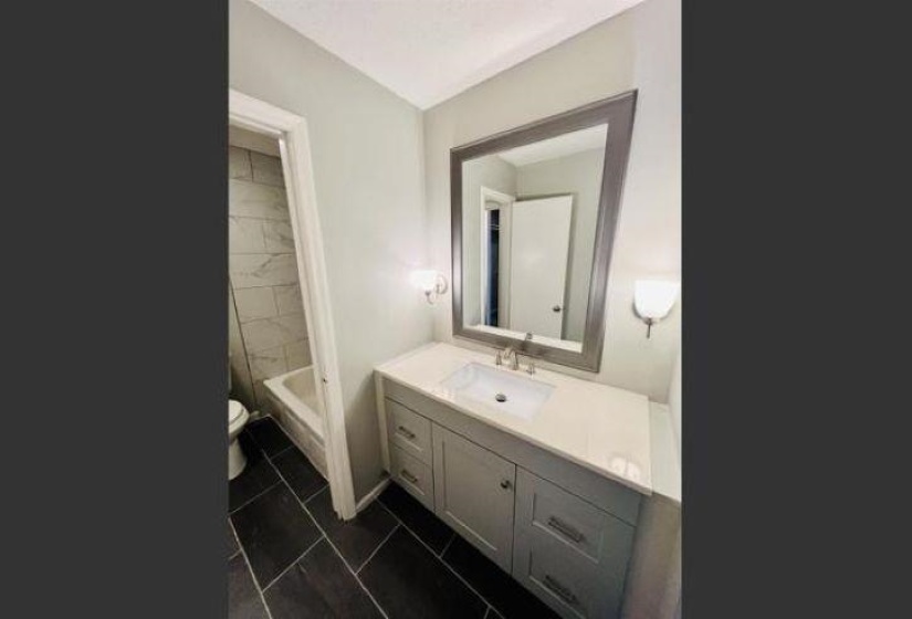 Full bath with vanity,  shower combination, and dark tile patterned flooring