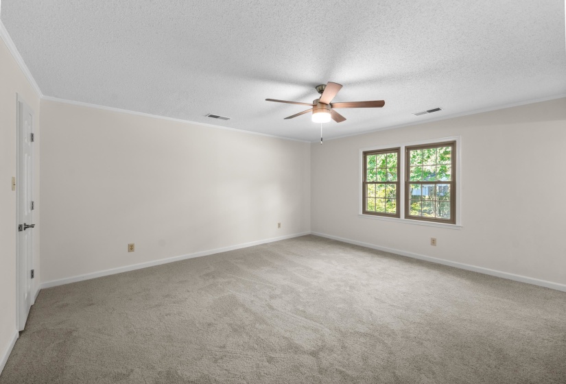 Empty room featuring ornamental molding, light colored carpet and a ceiling fan