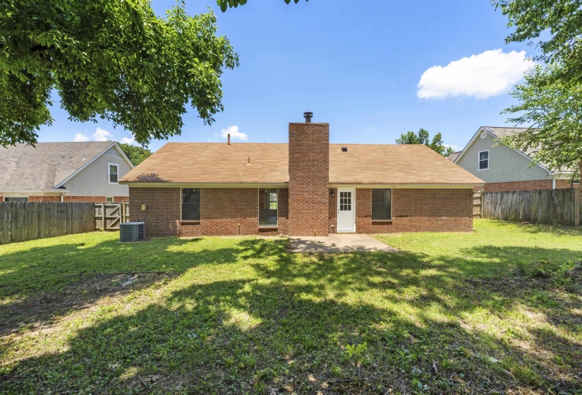 Rear view of property featuring a fenced backyard, brick siding, a chimney, and a patio