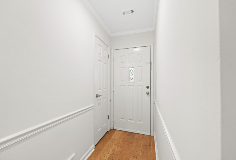 Doorway featuring crown molding and light wood finished floors