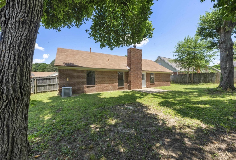 Back of house featuring brick siding, a fenced backyard, and a chimney