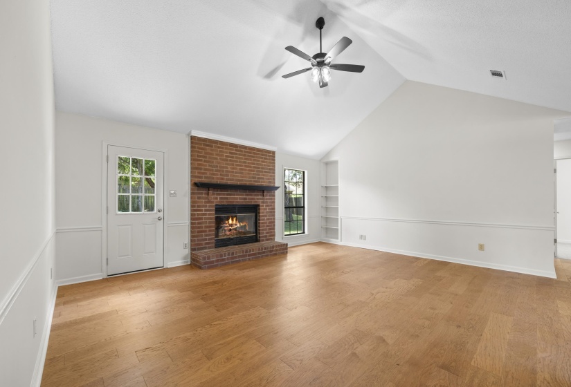 living room with built in shelves, lofted ceiling, light wood-style floors, ceiling fan, and a fireplace