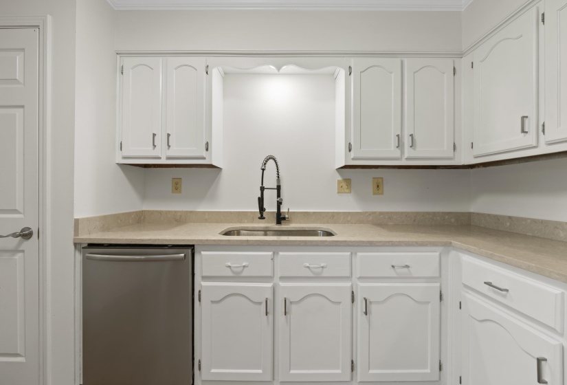 Kitchen featuring dishwasher, white cabinetry, quartz countertops, and crown molding