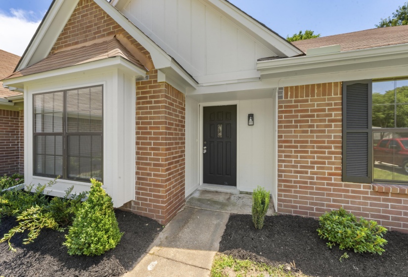 Doorway to property with brick siding and roof with shingles