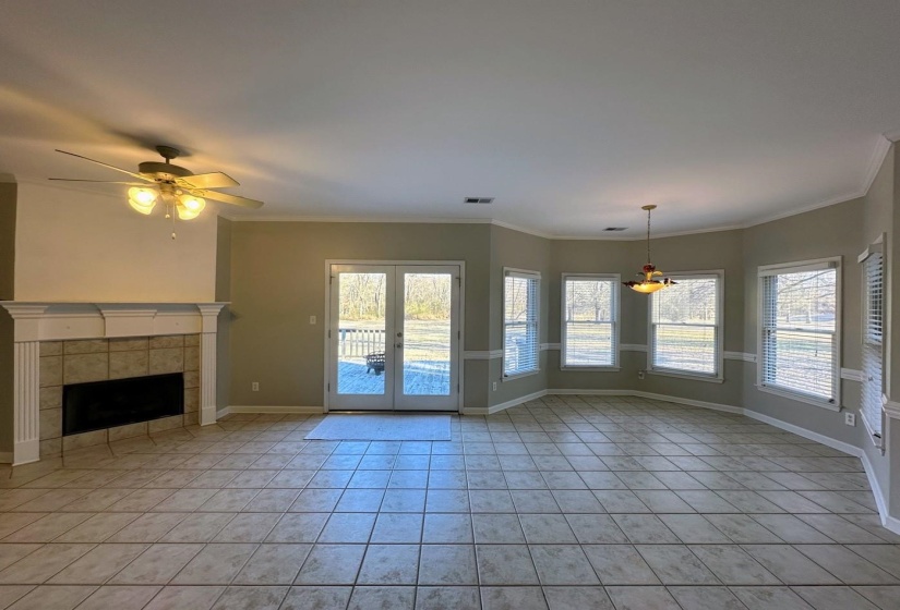 Unfurnished living room featuring french doors, a tile fireplace, ceiling fan, light tile patterned floors, and crown molding