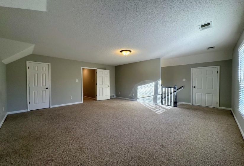 Carpeted empty room featuring a textured ceiling and baseboards
