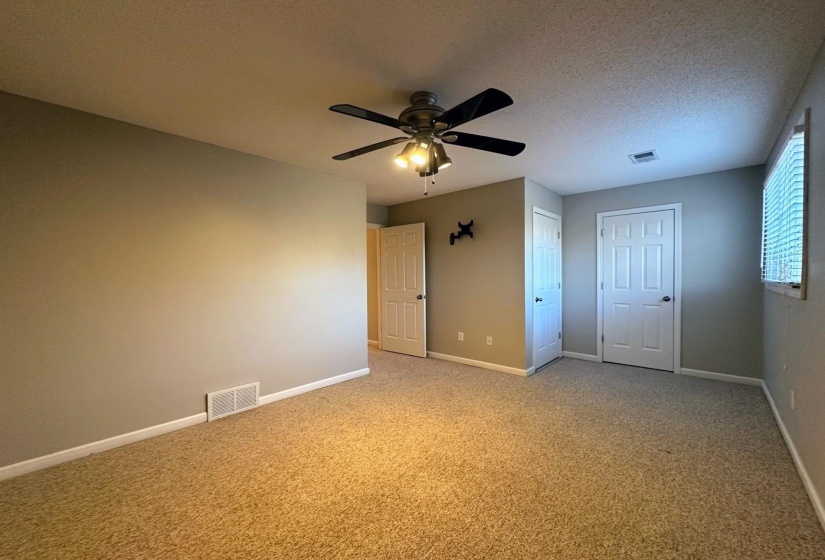Unfurnished bedroom featuring light colored carpet, ceiling fan, a textured ceiling, and a closet