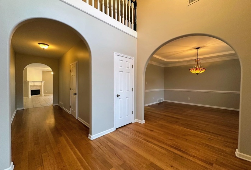 Hall featuring arched walkways, dark wood finished floors, and a towering ceiling