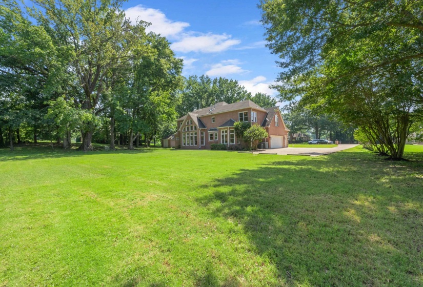 View of green lawn with an attached garage and driveway