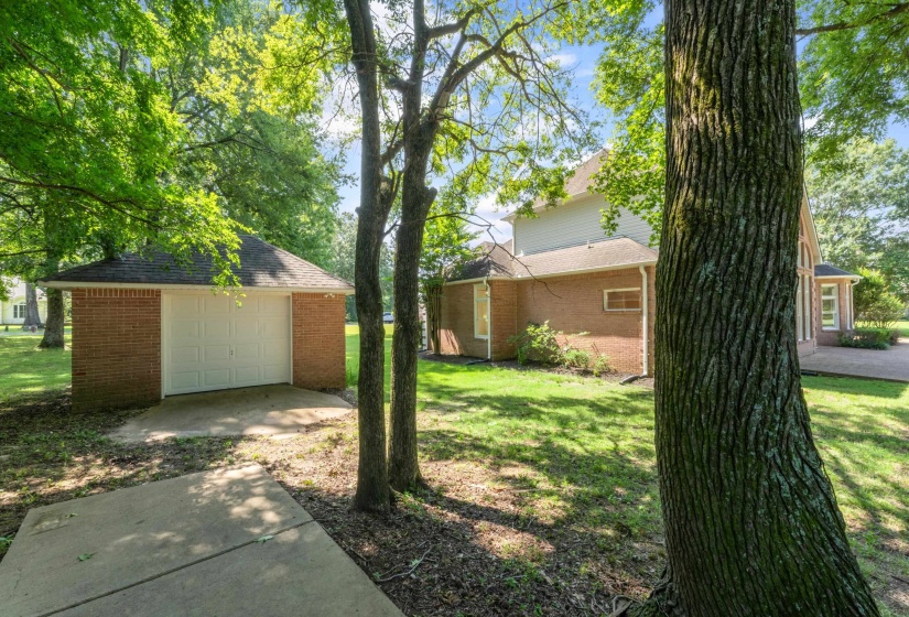 View of green lawn featuring a garage and an outbuilding