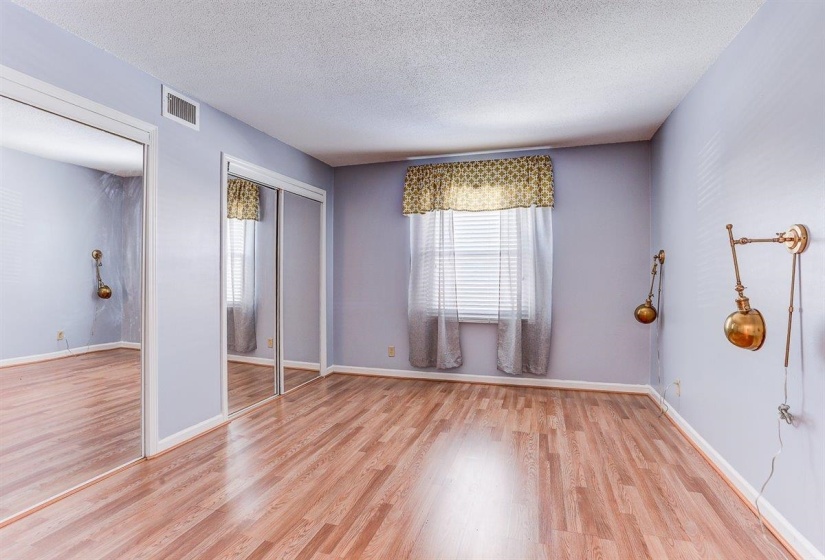 Unfurnished bedroom with light wood-type flooring, a textured ceiling, and two closets