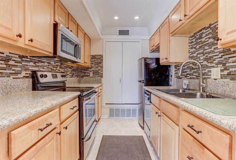 Kitchen with light brown cabinets, stainless steel appliances, recessed lighting, light tile patterned floors, and tasteful backsplash