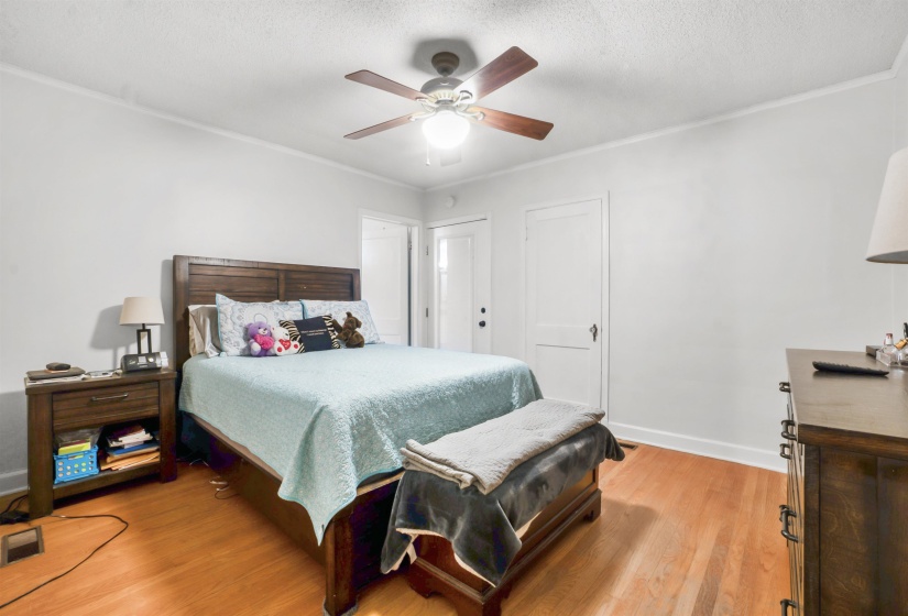 Bedroom featuring light wood-style floors, a textured ceiling, ceiling fan, and ornamental molding