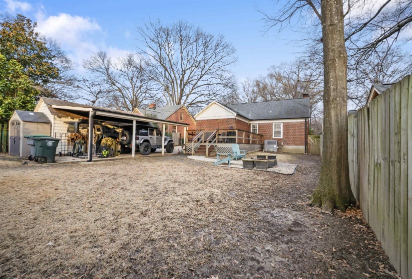 Rear view of house featuring a storage unit, a chimney, a fenced backyard, a sunroom, and brick siding