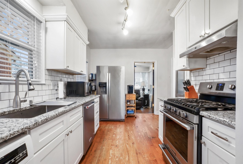 Kitchen featuring stainless steel appliances, under cabinet range hood, white cabinets, and light wood finished floors