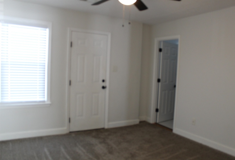 Unfurnished bedroom featuring multiple windows, dark carpet, and ceiling fan