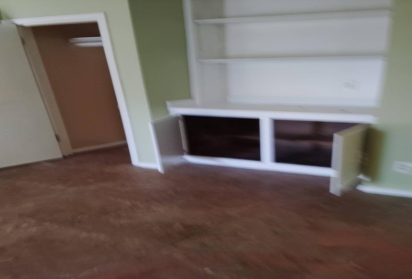 Unfurnished living room featuring dark carpet and built in shelves