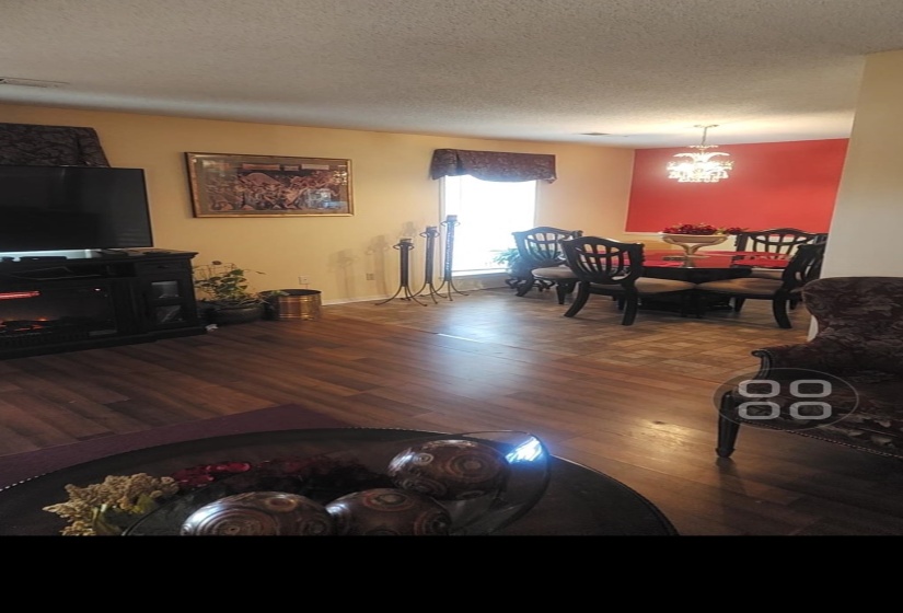 Living room with dark wood-style flooring, a textured ceiling, and a chandelier