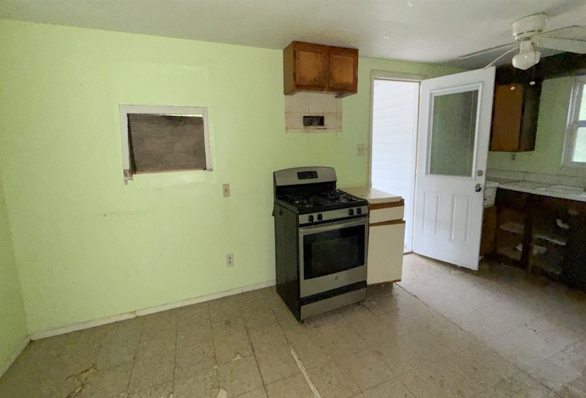 Kitchen space featuring a freestanding range, wood-finish upper cabinetry, and a glass-paneled exterior door