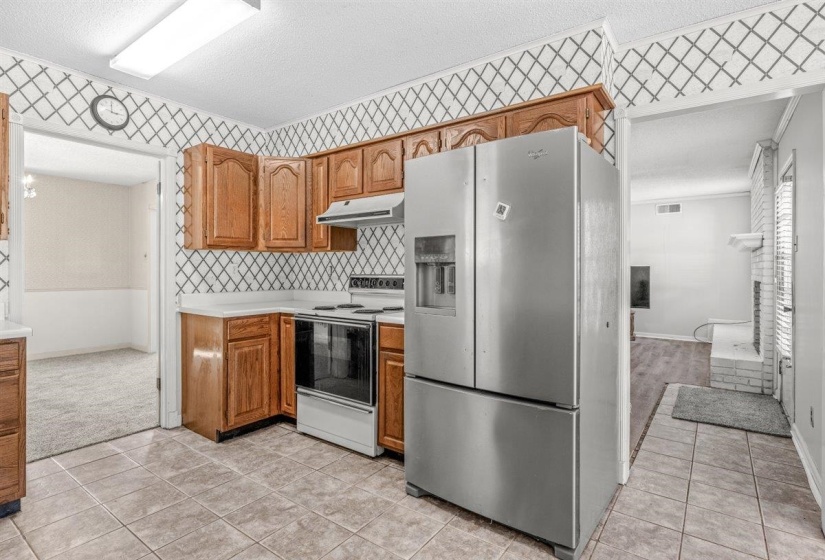 Kitchen featuring stainless steel fridge with ice dispenser, light countertops, electric stove, a textured ceiling, and light tile patterned floors