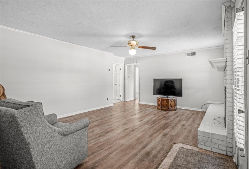 Living area with wood finished floors, a textured ceiling, ceiling fan, and ornamental molding