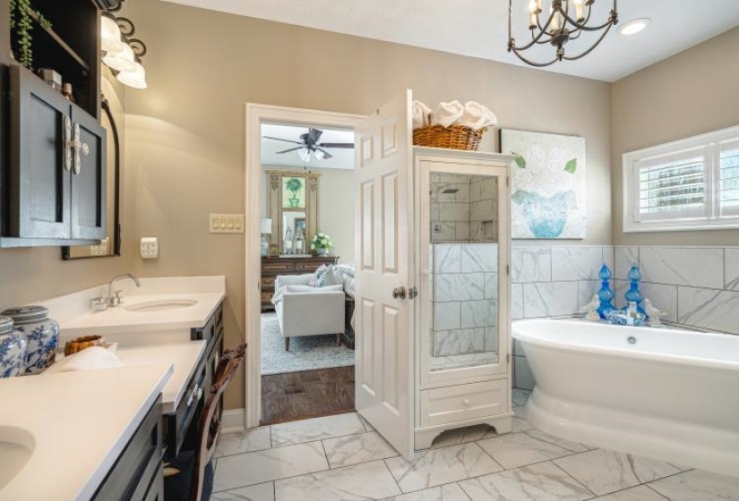 Full bathroom featuring a soaking tub, ensuite bathroom, marble finish floor, an inviting chandelier, and vanity