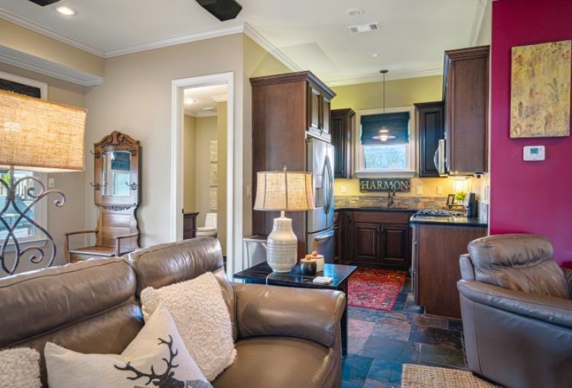 Kitchen with stainless steel appliances, dark countertops, visible vents, hanging light fixtures, and ornamental molding