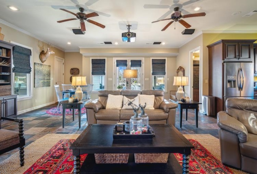 Living area featuring ornamental molding, a wealth of natural light, baseboards, and stone tile floors