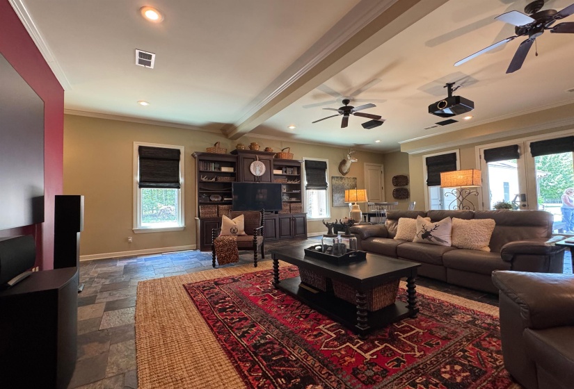 Living room featuring ceiling fan, ornamental molding, stone tile flooring, and recessed lighting